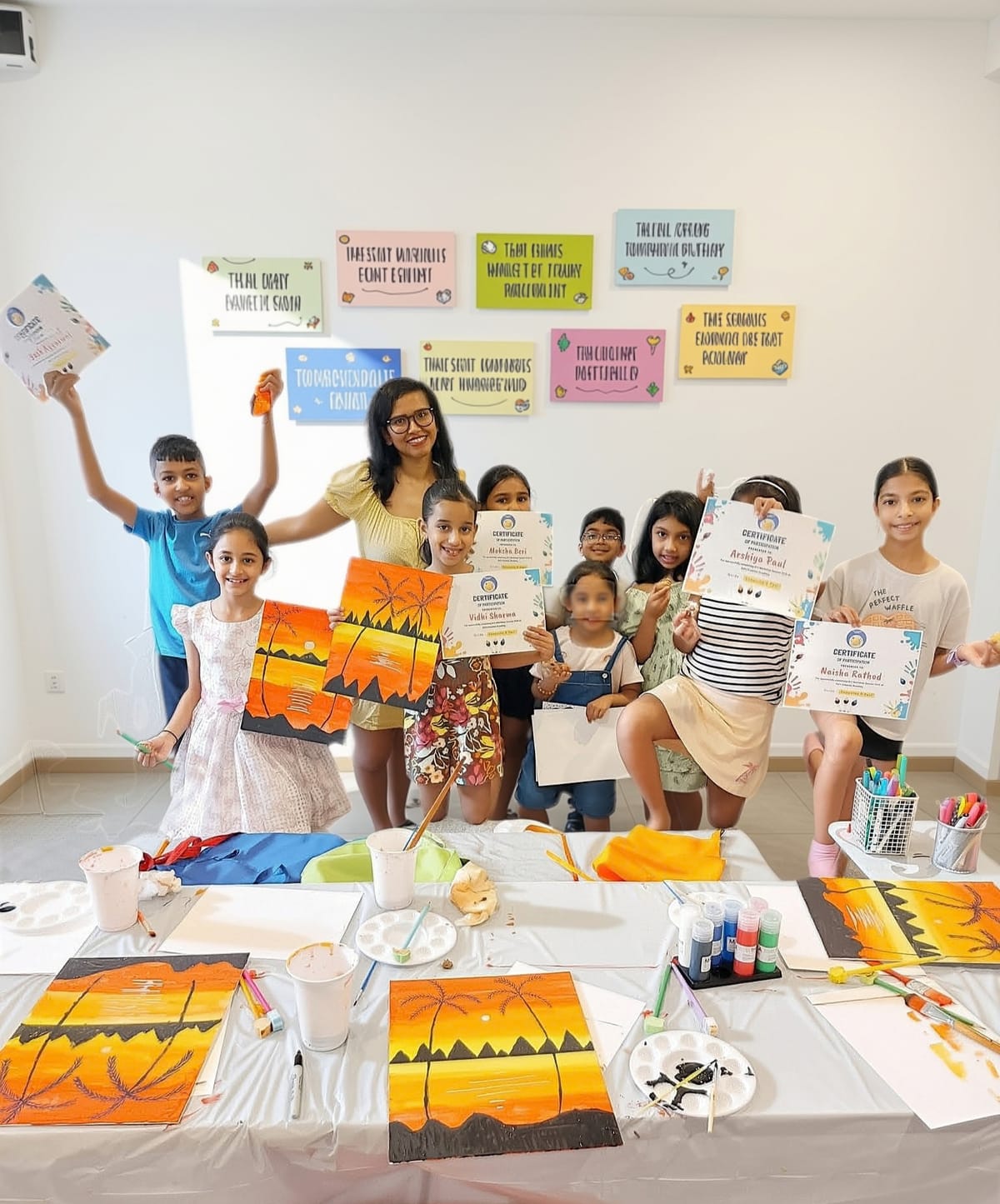 KCA Art Club children holding up their sunset paintings and certificates