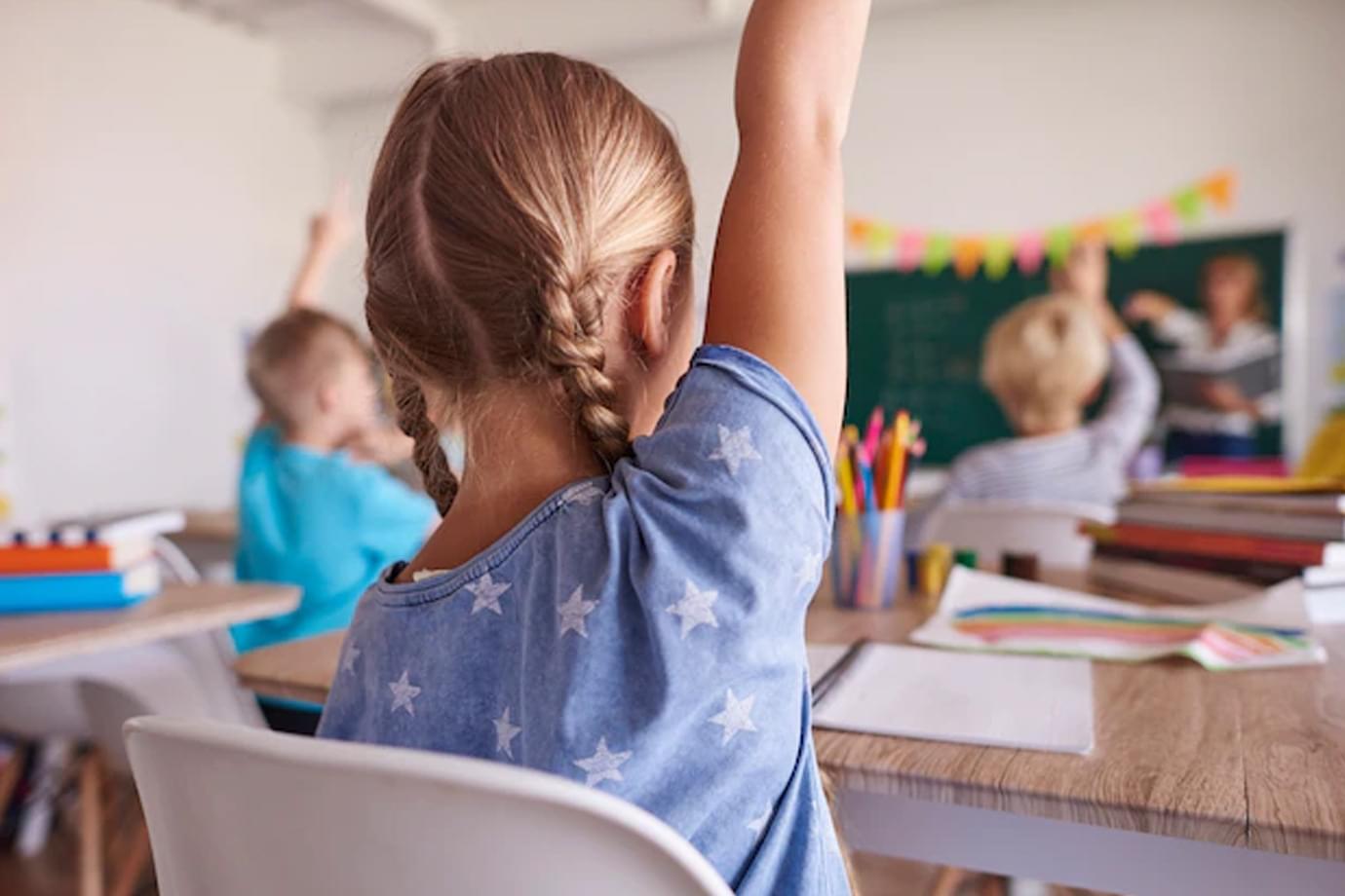 A child raising a hand to ask a question in class